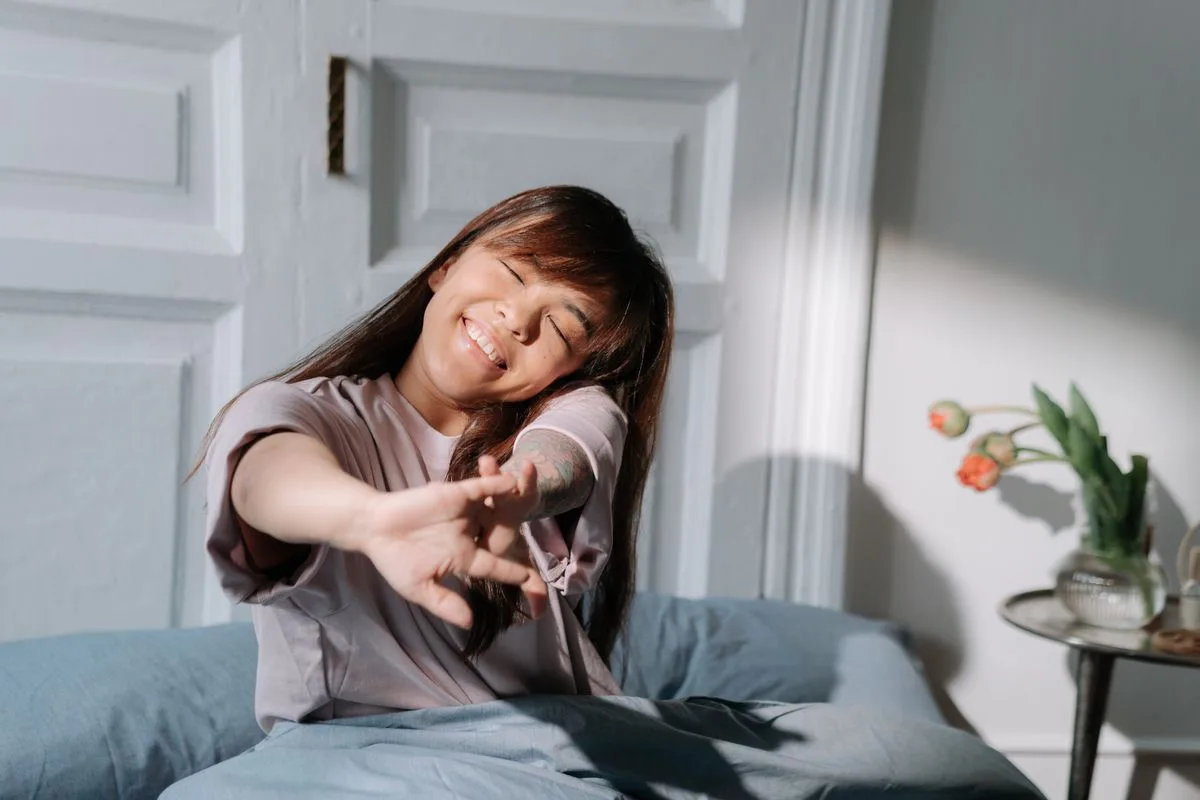 Woman stretching and waking up naturally in morning light — circadian biology