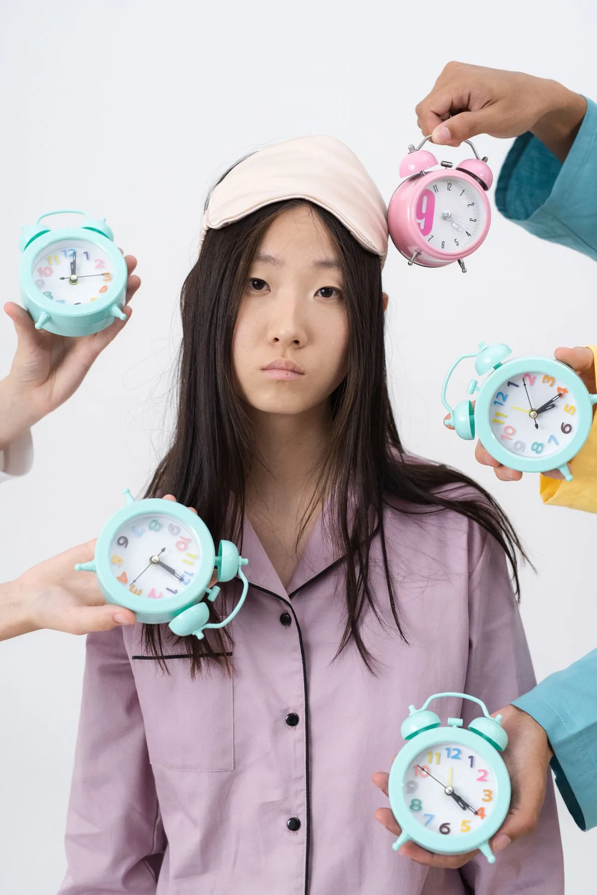 Woman in pajamas surrounded by alarm clocks, illustrating insomnia and sleep disruption