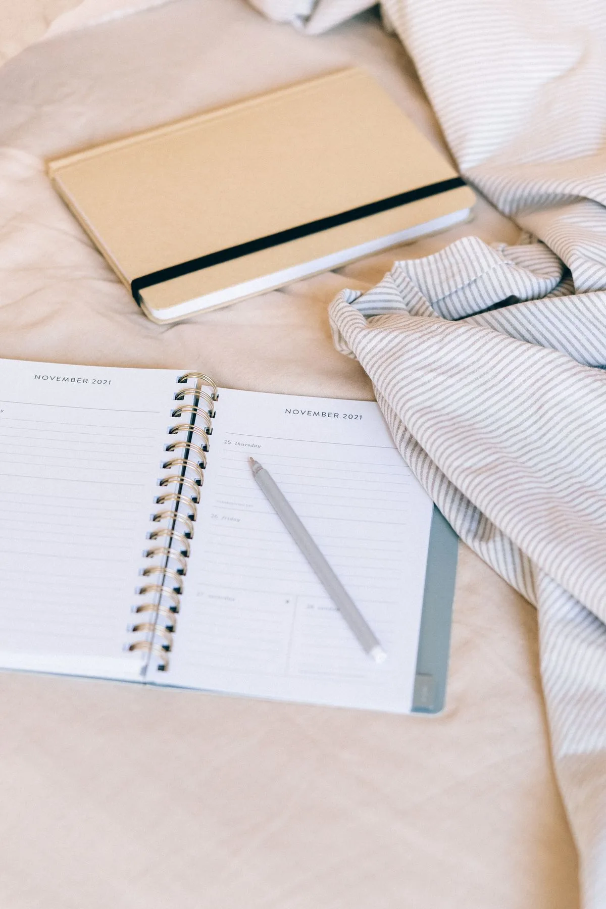 Open planner with pen and notebook on a cozy desk, representing daily routine and habit tracking