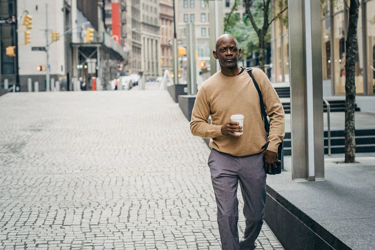 Self-assured mature man walking on city street with takeaway coffee during a work break