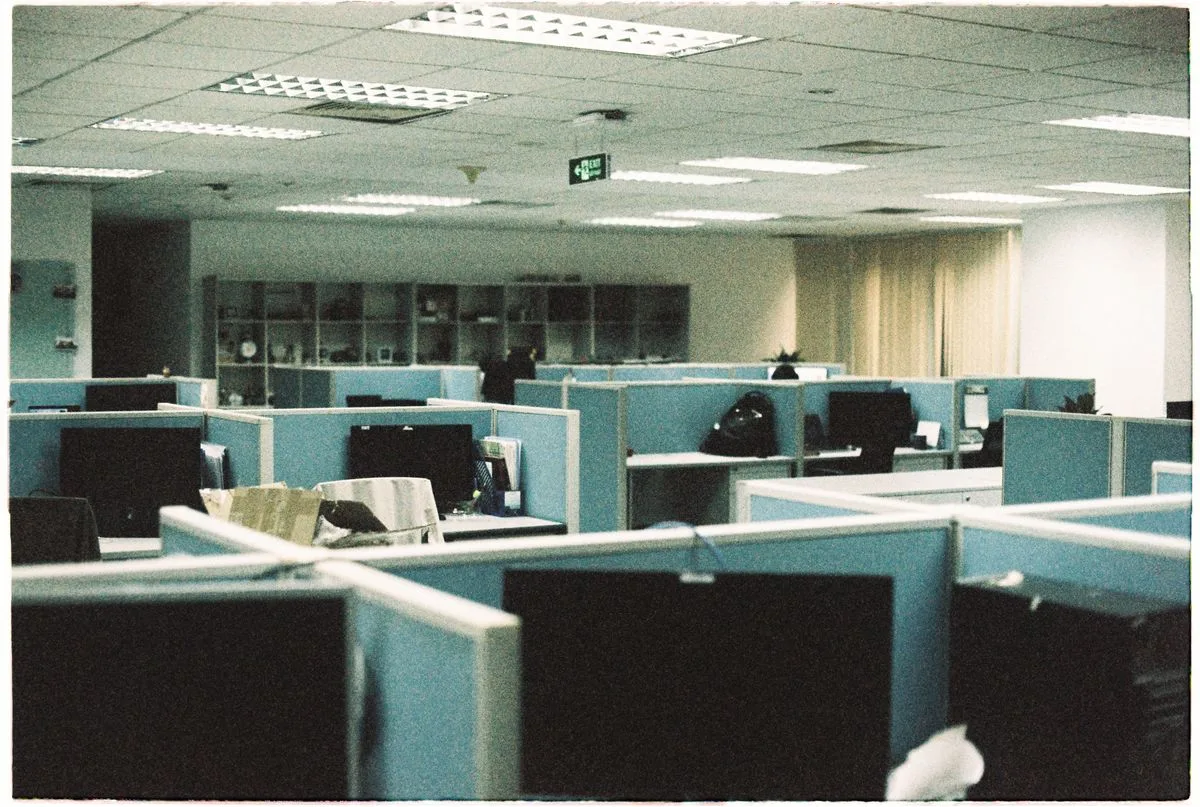 Spacious office floor with rows of empty cubicles and computer monitors — workplace circadian disruption