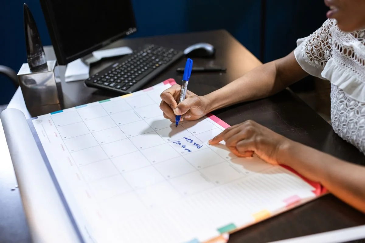 Person writing notes in desk calendar — time blocking by biological peak hours