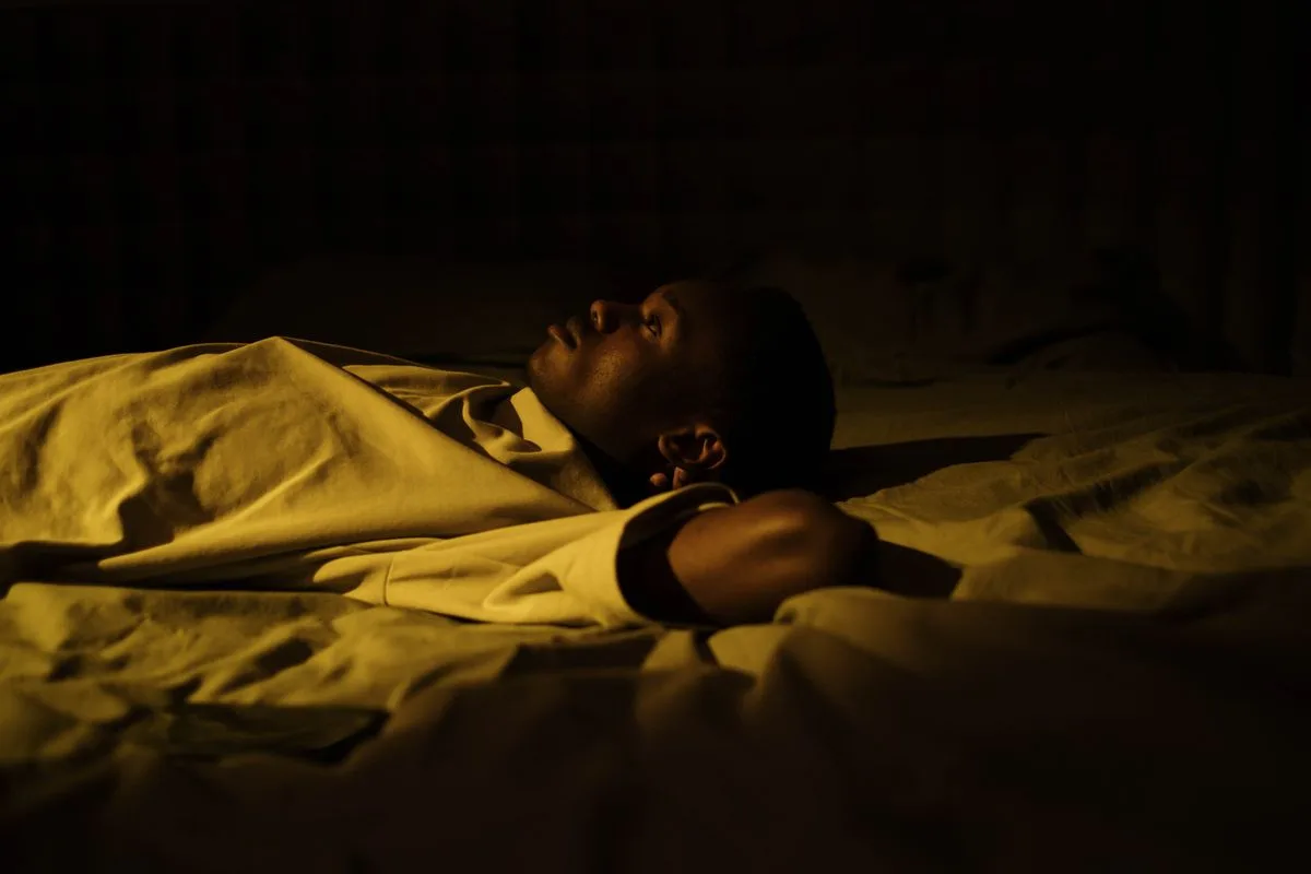 Man lying awake in dark bedroom at night — magnesium deficiency and sleep disruption