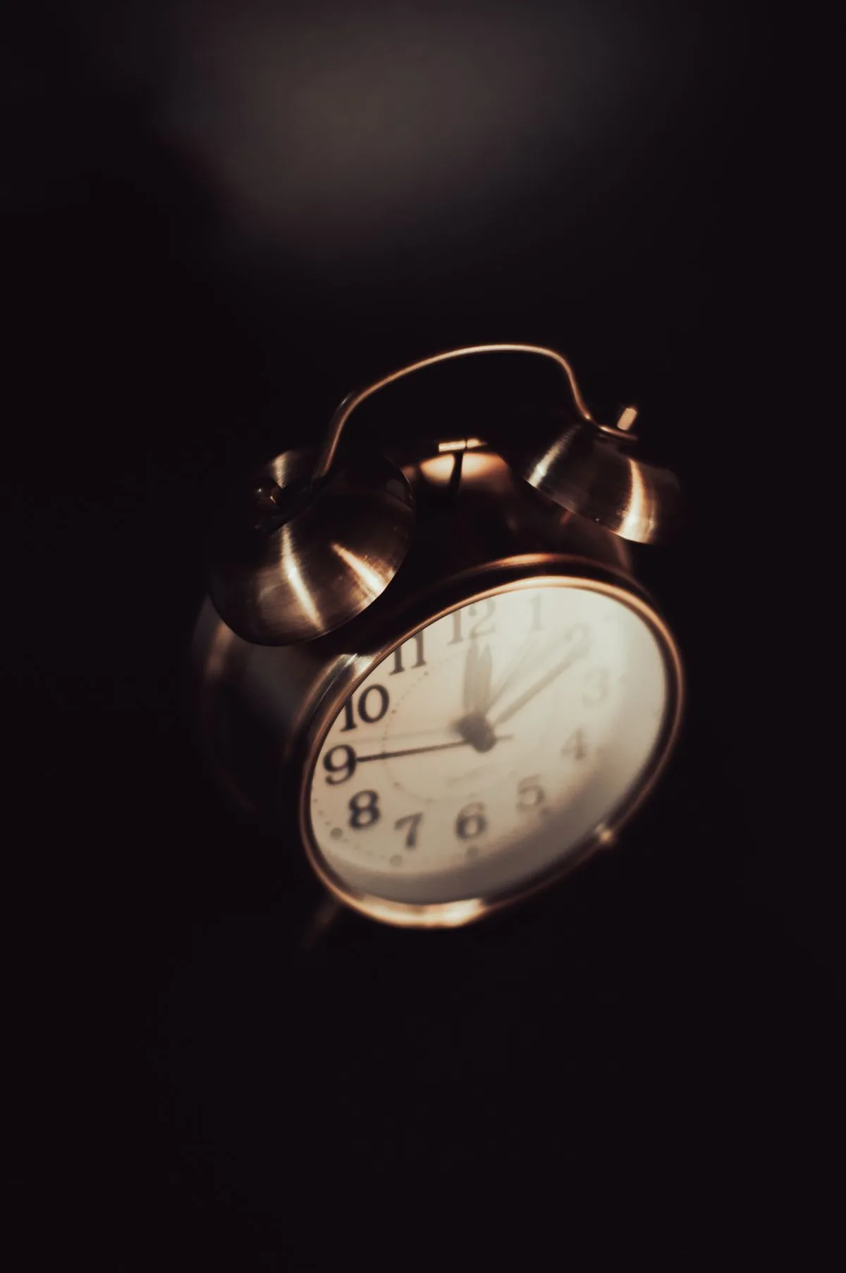 Vintage brass alarm clock in dimly lit setting — timing window for magnesium before sleep