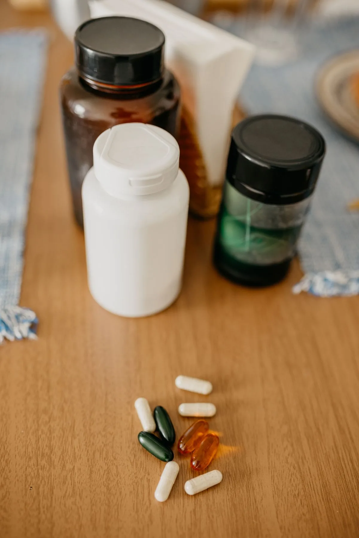 Assorted supplement bottles and capsules on wooden surface — magnesium glycinate vs oxide forms