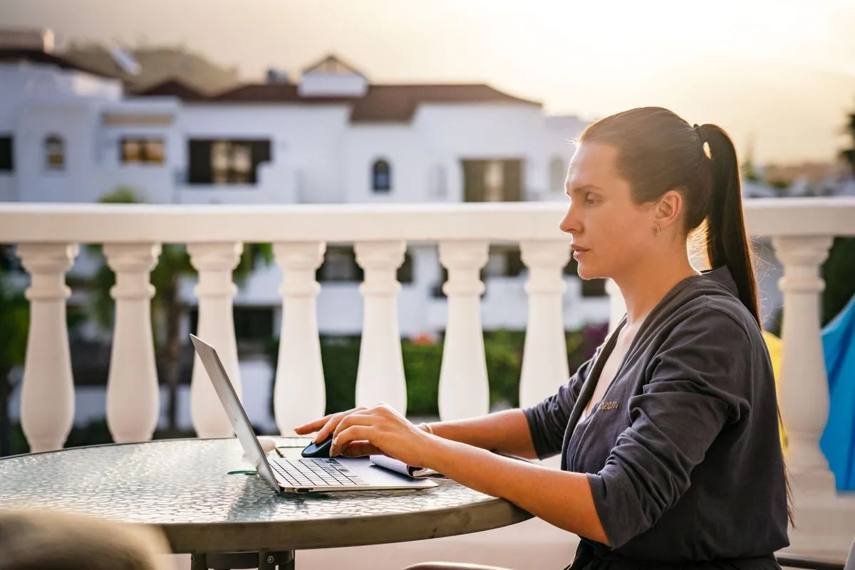 Woman working on laptop on sunny balcony in the morning — morning chronotype productivity schedule